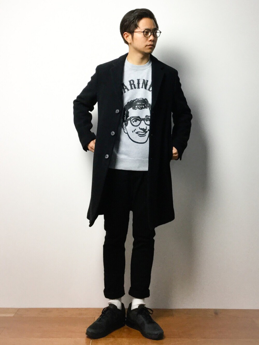 グレー系のスウェット、ブラック系のスニーカー、ブラック系のチェスターコートを着用したメンズの冬コーディネートの1枚目の写真