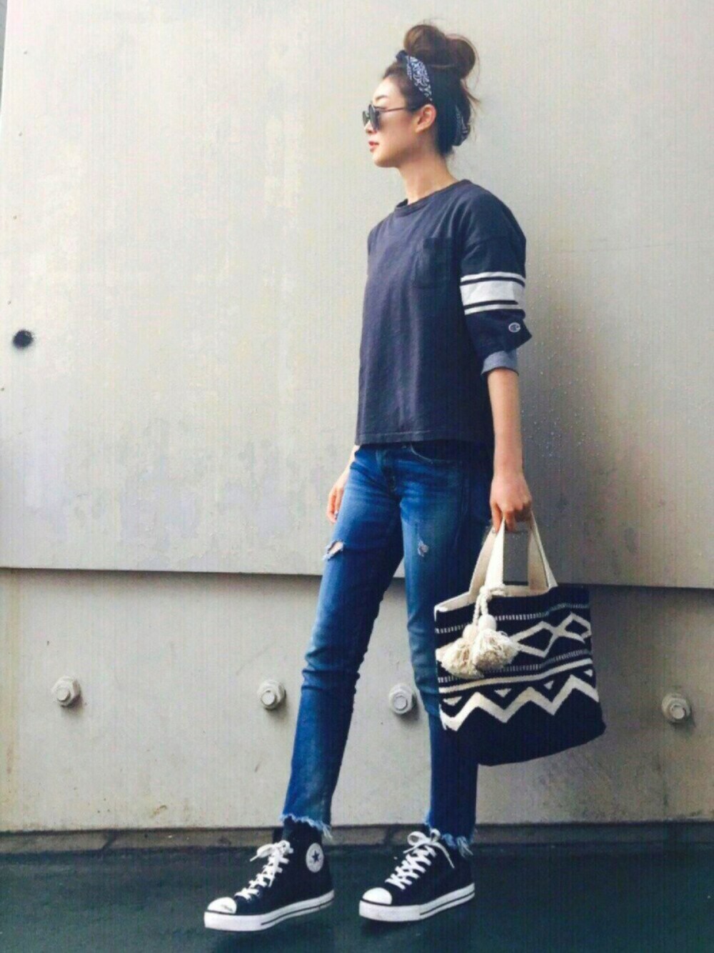 ブラック系のTシャツ/カットソー、グレー系のニット/セーター、ブルー系のデニムパンツを着用したレディースの春コーディネートの1枚目の写真