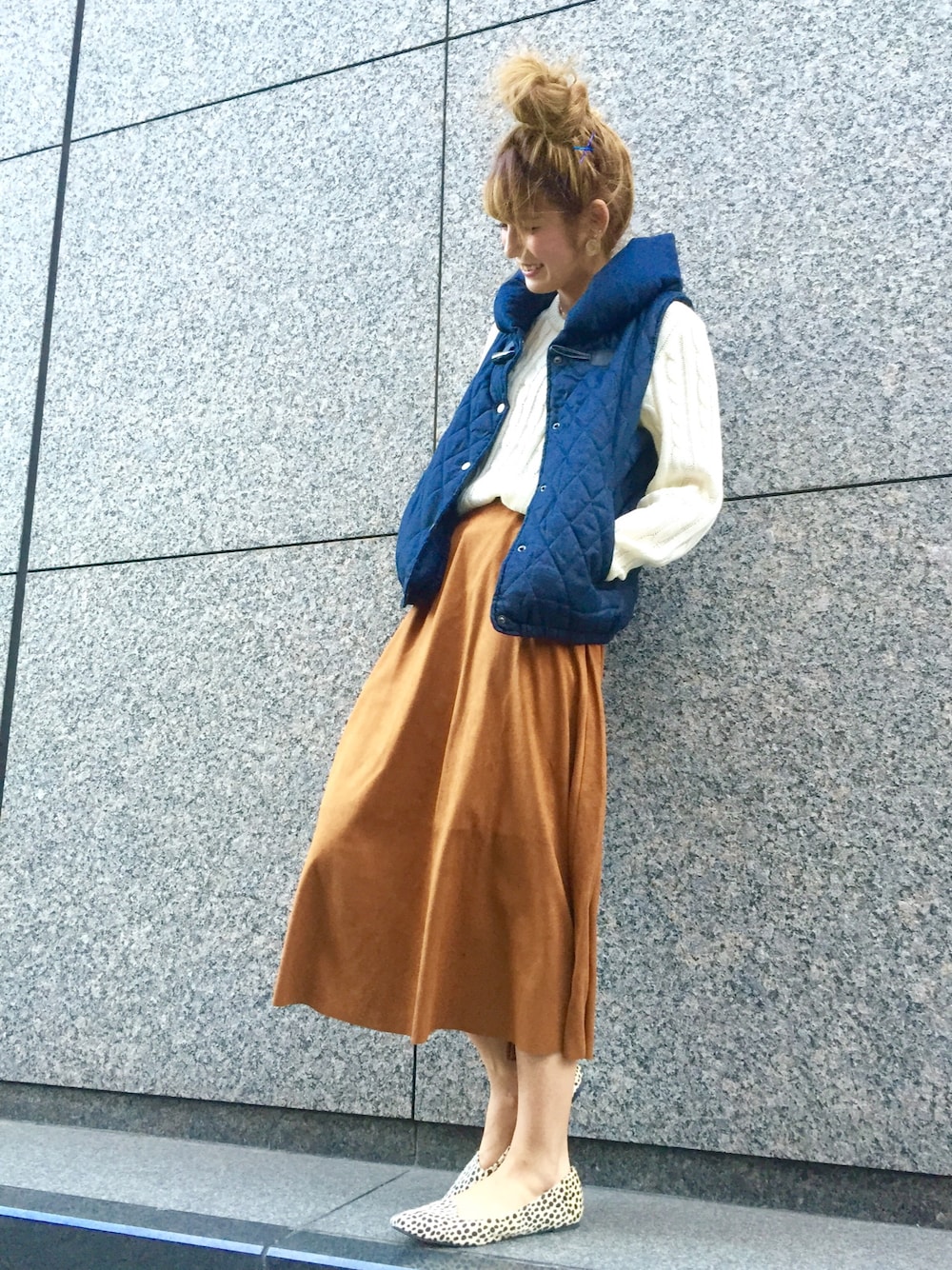 ブルー系のダウンベスト、ホワイト系のニット/セーター、ブラウン系のスカートを着用したレディースの冬コーディネートの1枚目の写真