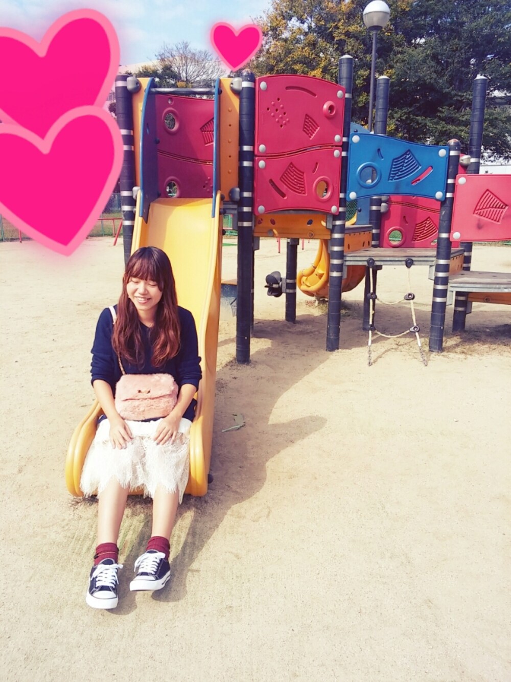 ピンク系のショルダーバッグ、ブルー系のチュニック、ブラック系のスニーカーを着用したレディースの秋コーディネートの1枚目の写真