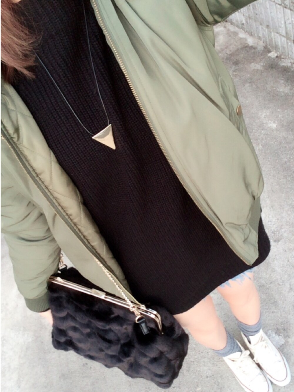 グリーン系のブルゾン、ブラック系のクラッチバッグ、ホワイト系のスニーカーを着用したレディースの冬コーディネートの1枚目の写真