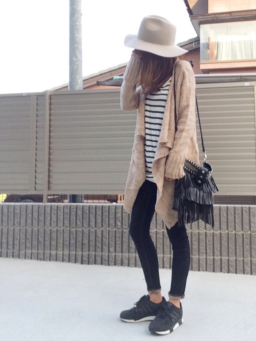 ベージュ系のニット/セーター、ホワイト系のワンピース、ブルー系のデニムパンツを着用したレディースの秋コーディネートの1枚目の写真