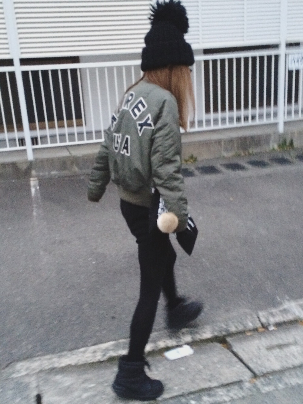 グリーン系のミリタリージャケット、ブラック系のワンピース、ブラック系のクラッチバッグを着用したレディースの冬コーディネートの1枚目の写真