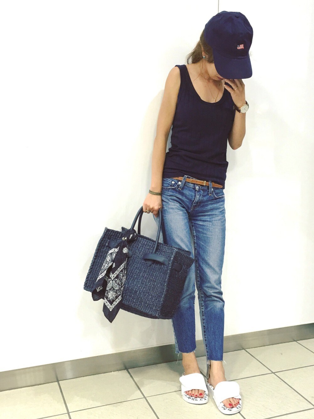 ブルー系のタンクトップ、ブルー系のかごバッグ、ブルー系のデニムパンツを着用したレディースの夏コーディネートの1枚目の写真