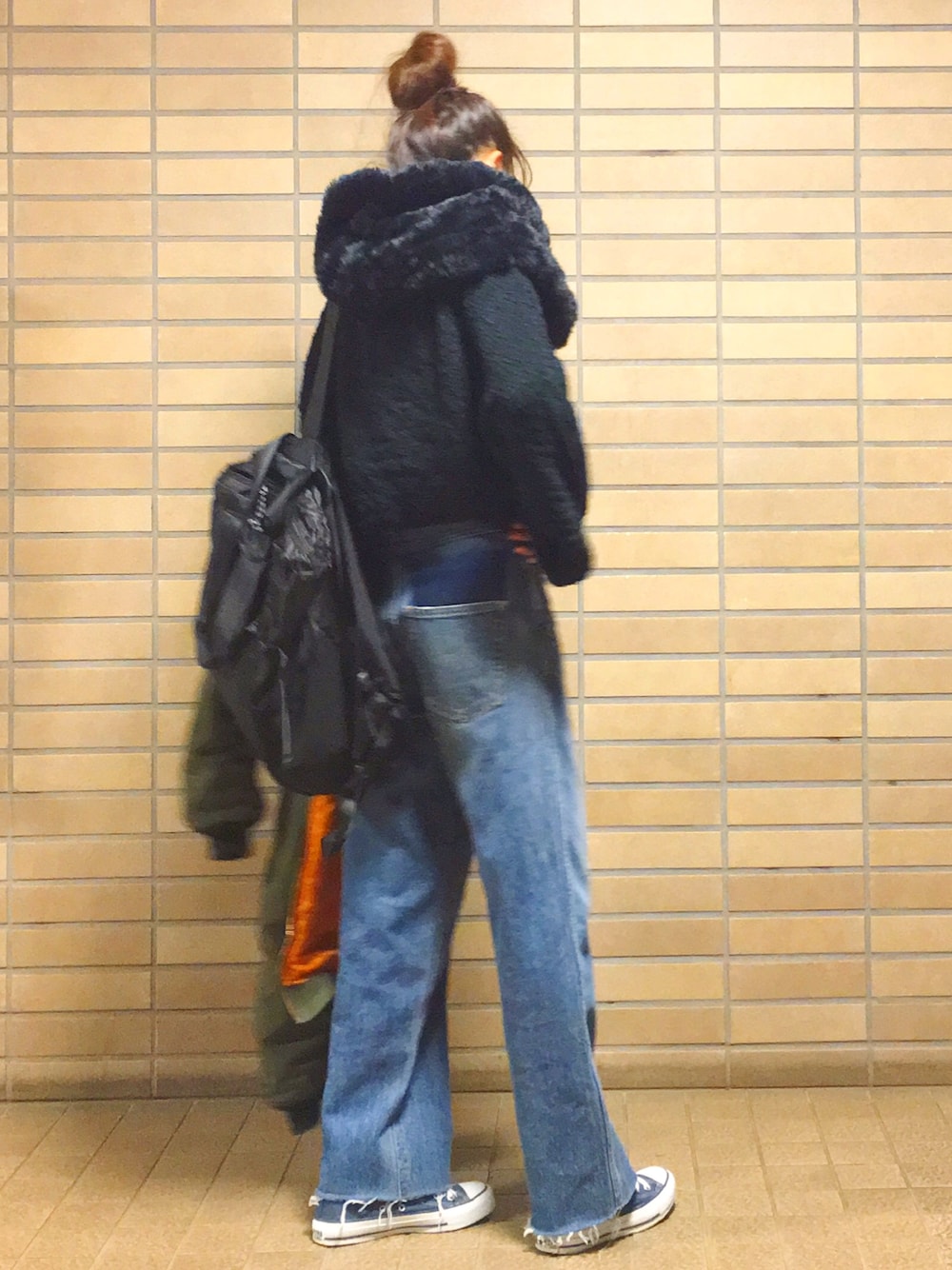 ブラック系のニット/セーター、ブルー系のデニムパンツ、ブラック系のバックパック/リュックを着用したレディースの冬コーディネートの1枚目の写真