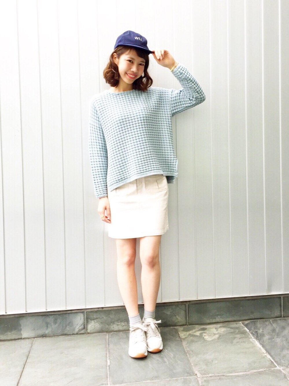 ブルー系のニット/セーター、ホワイト系のスカート、グレー系のスニーカーを着用したレディースの冬コーディネートの1枚目の写真