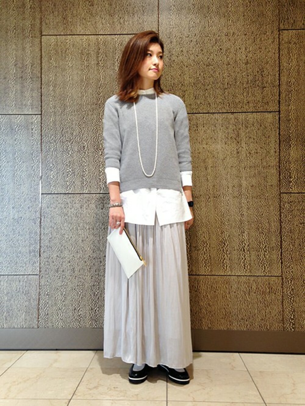 グレー系のニット/セーター、ホワイト系のシャツ/ブラウス、グレー系のスカートを着用したメンズの秋コーディネートの1枚目の写真