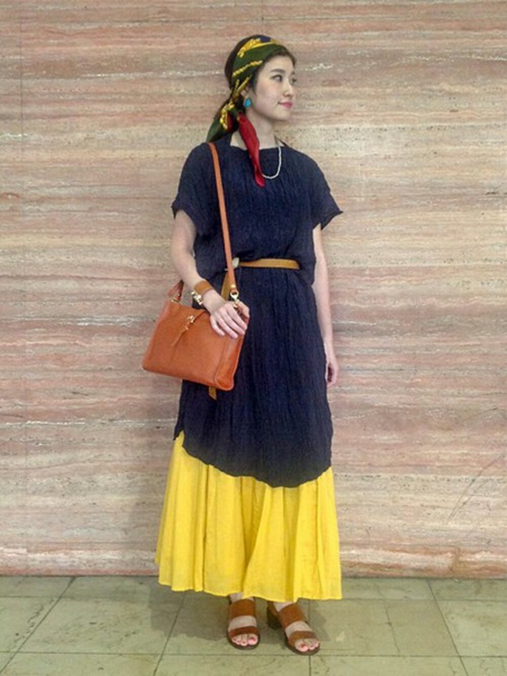 イエロー系のスカート、ブラウン系のショルダーバッグ、ブラウン系のサンダルを着用したレディースの春コーディネートの1枚目の写真