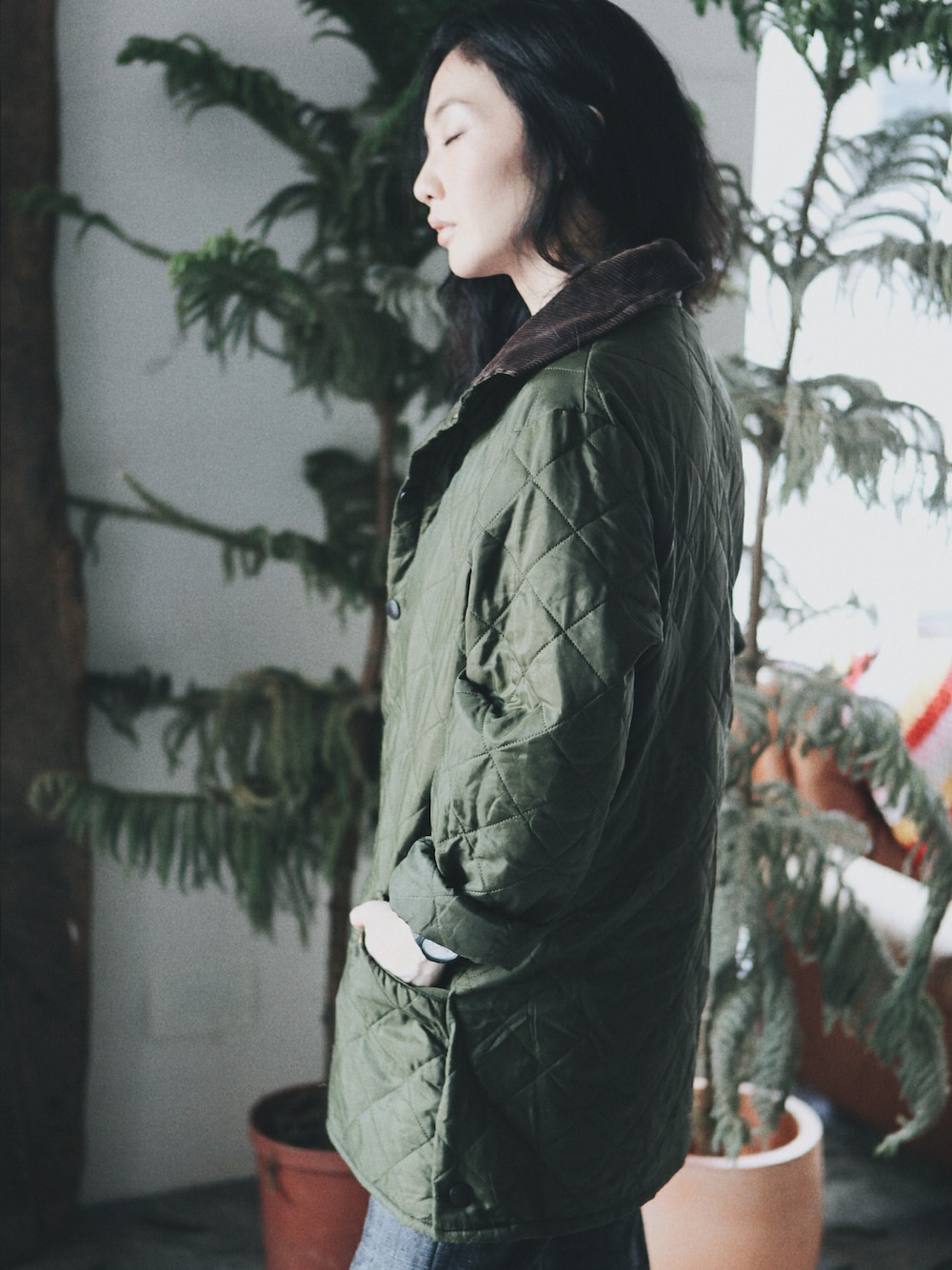 グリーン系のナイロンジャケットを着用したレディースの冬コーディネートの1枚目の写真