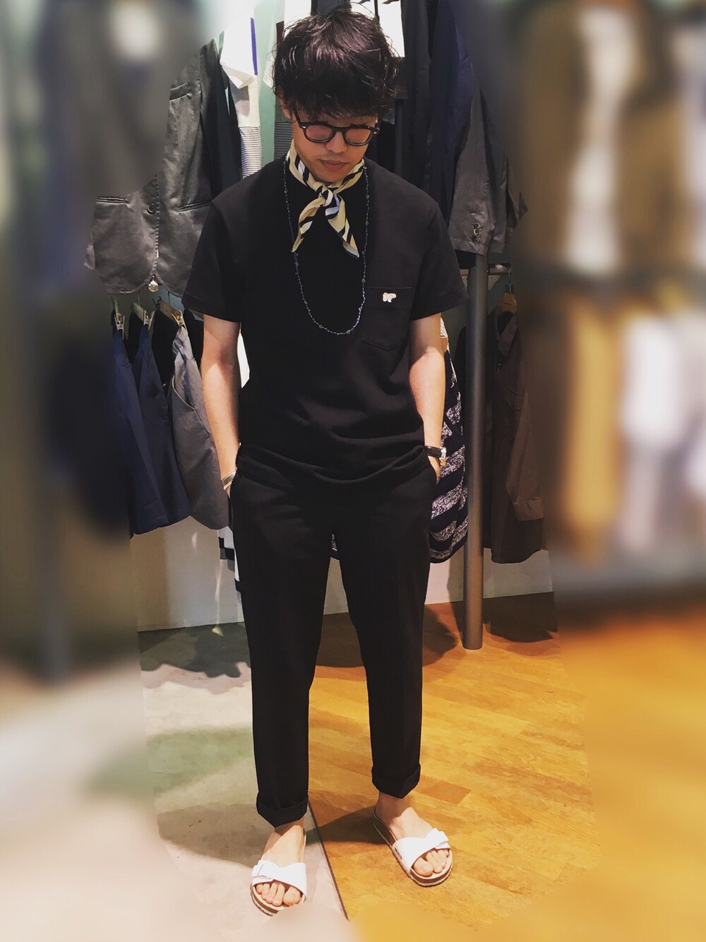 ブラック系のTシャツ/カットソー、ブラック系のスラックス、ホワイト系のサンダルを着用したメンズの春コーディネートの1枚目の写真