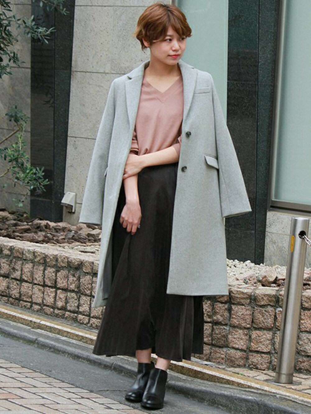 グレー系のチェスターコート、ピンク系のニット/セーター、グレー系のスカートを着用したレディースの秋コーディネートの1枚目の写真