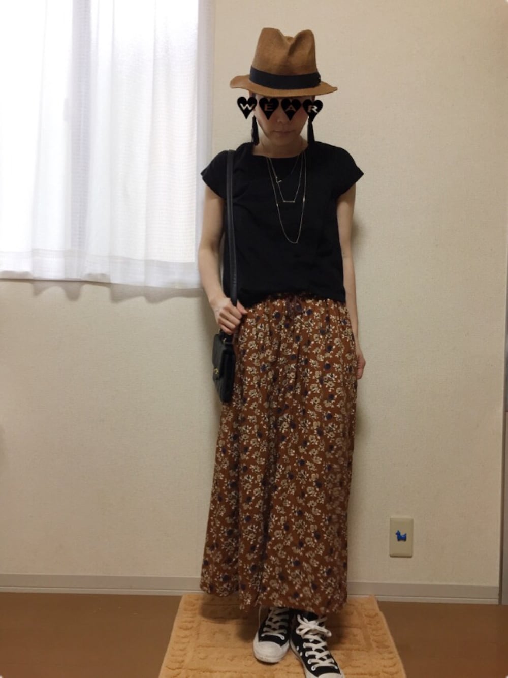 ブラック系のTシャツ/カットソー、ブラウン系のスカート、ブラック系のスニーカーを着用したレディースの春コーディネートの1枚目の写真