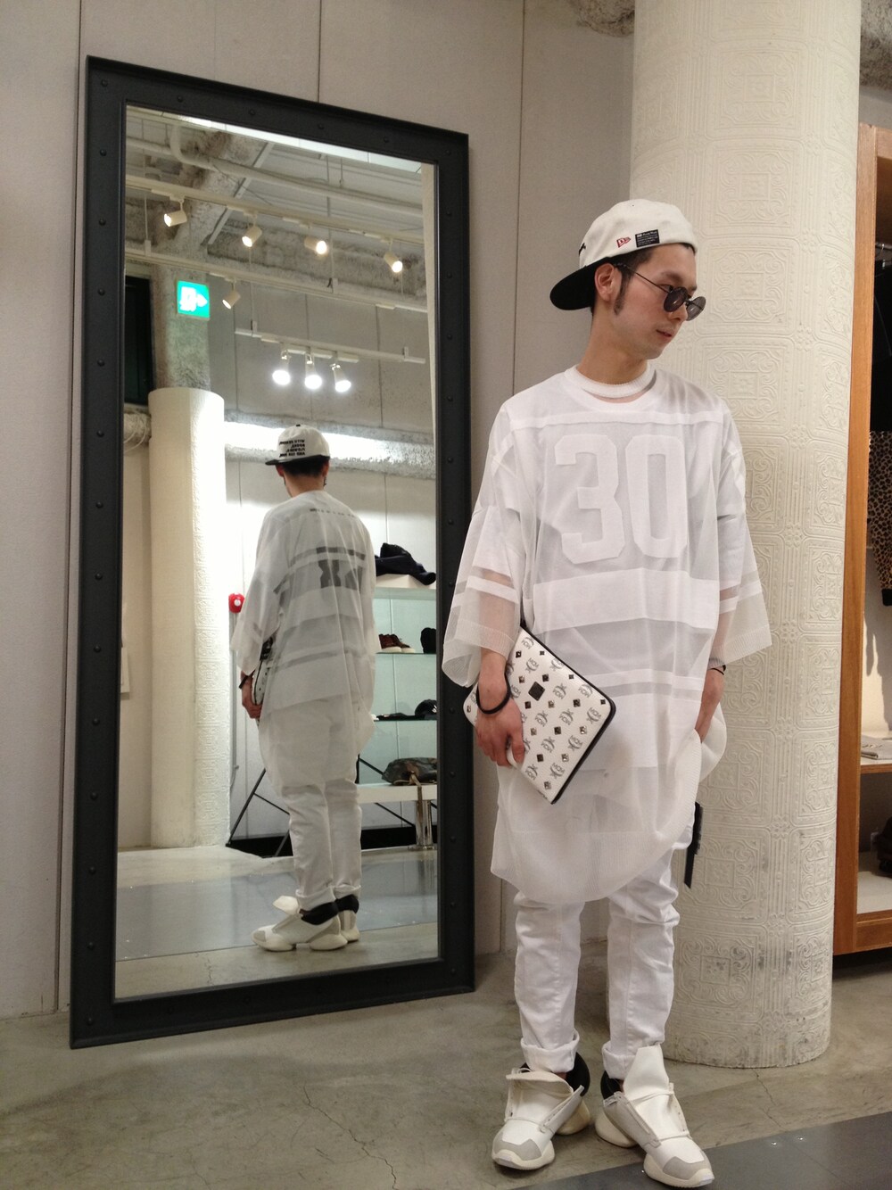 ホワイト系のクラッチバッグ、ホワイト系のTシャツ/カットソー、ブラック系のサングラスを着用したメンズの冬コーディネートの1枚目の写真