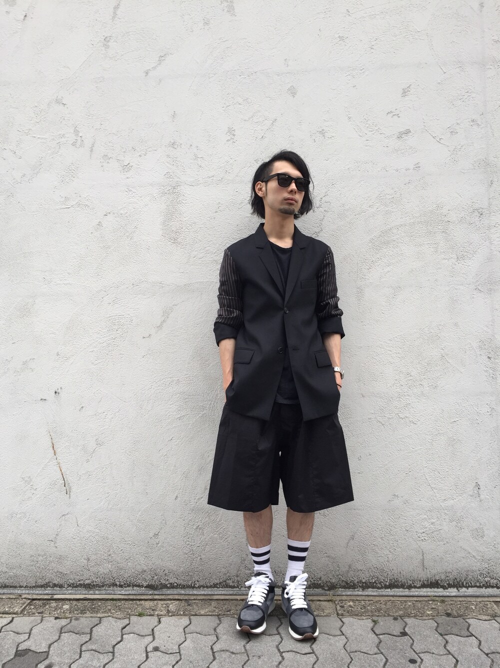 ブラック系のテーラードジャケット、ブラック系のその他パンツ、グレー系のスニーカーを着用したメンズの夏コーディネートの1枚目の写真