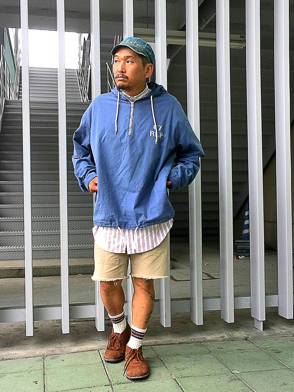 ブラウン系のブーツ、ホワイト系のトップス、ブルー系のマウンテンパーカーを着用したメンズの夏コーディネートの1枚目の写真
