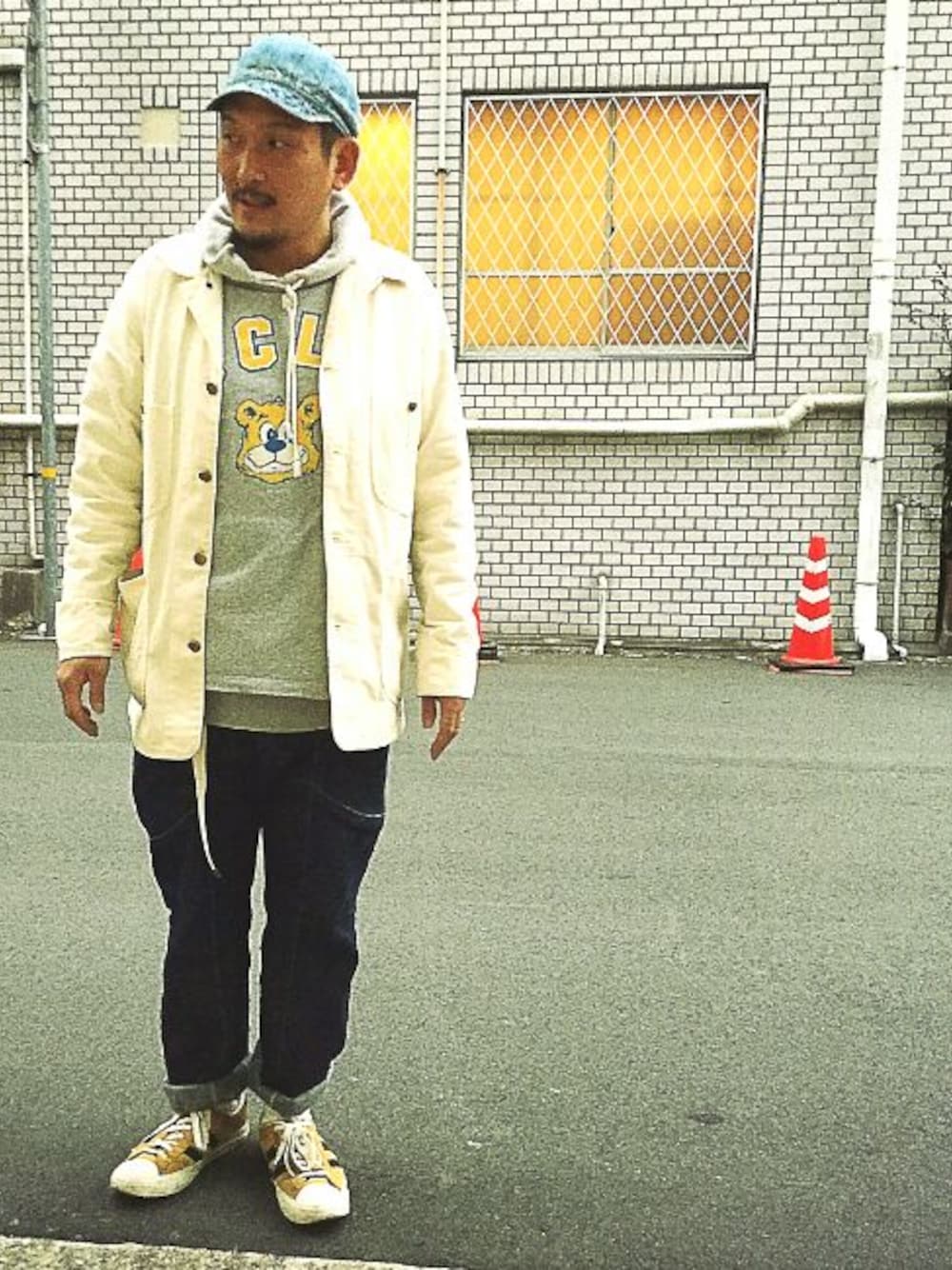 ゴールド系のスニーカー、ブルー系のデニムパンツ、グレー系のトップスを着用したメンズの冬コーディネートの1枚目の写真