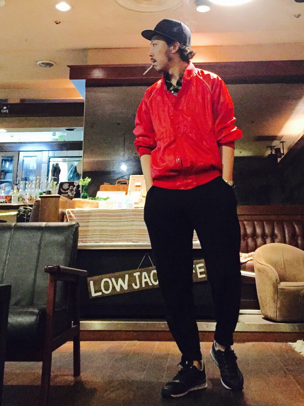 レッド系のナイロンジャケット、ブラック系のポロシャツ、ブラック系のスニーカーを着用したメンズの春コーディネートの1枚目の写真