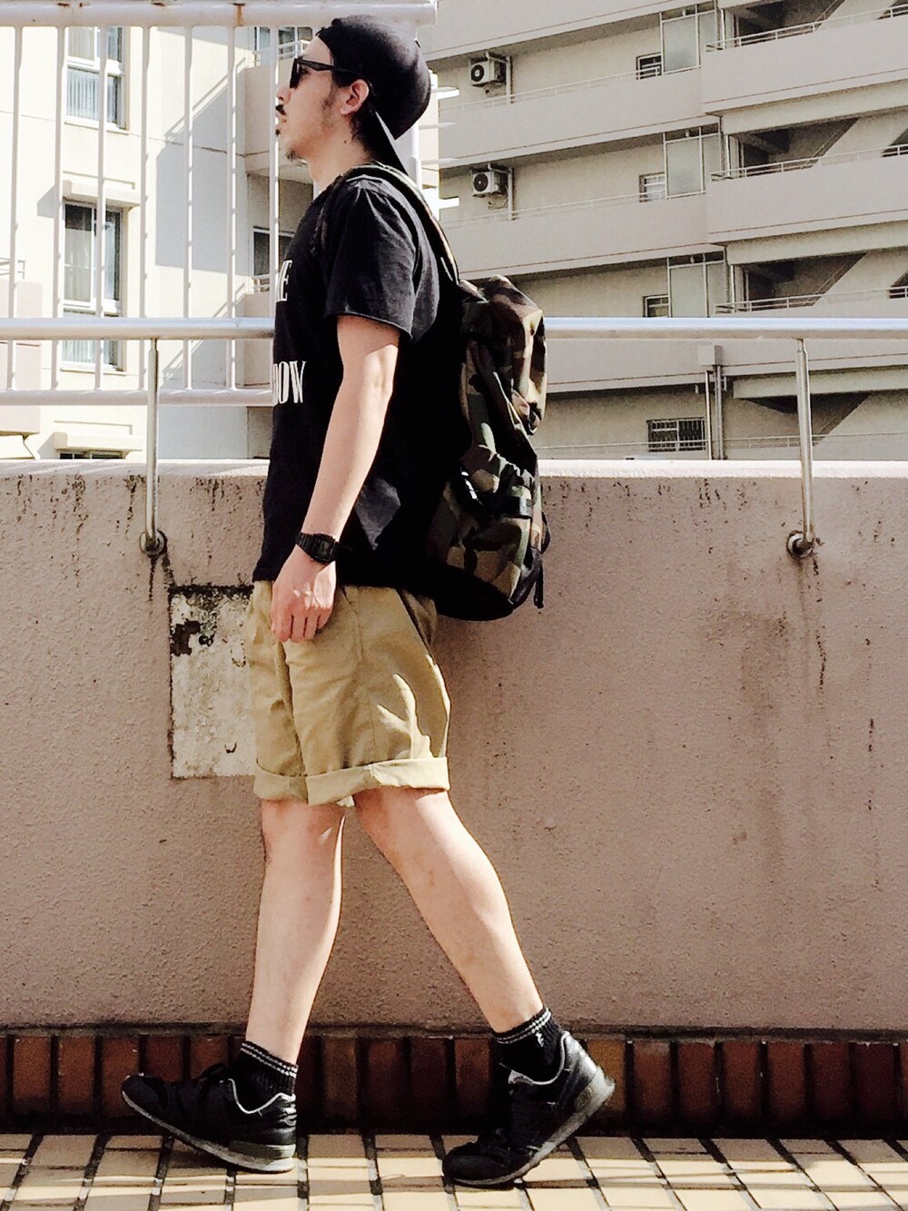 ブラック系のTシャツ/カットソー、ブラック系のスニーカー、その他のバックパック/リュックを着用したメンズの夏コーディネートの1枚目の写真