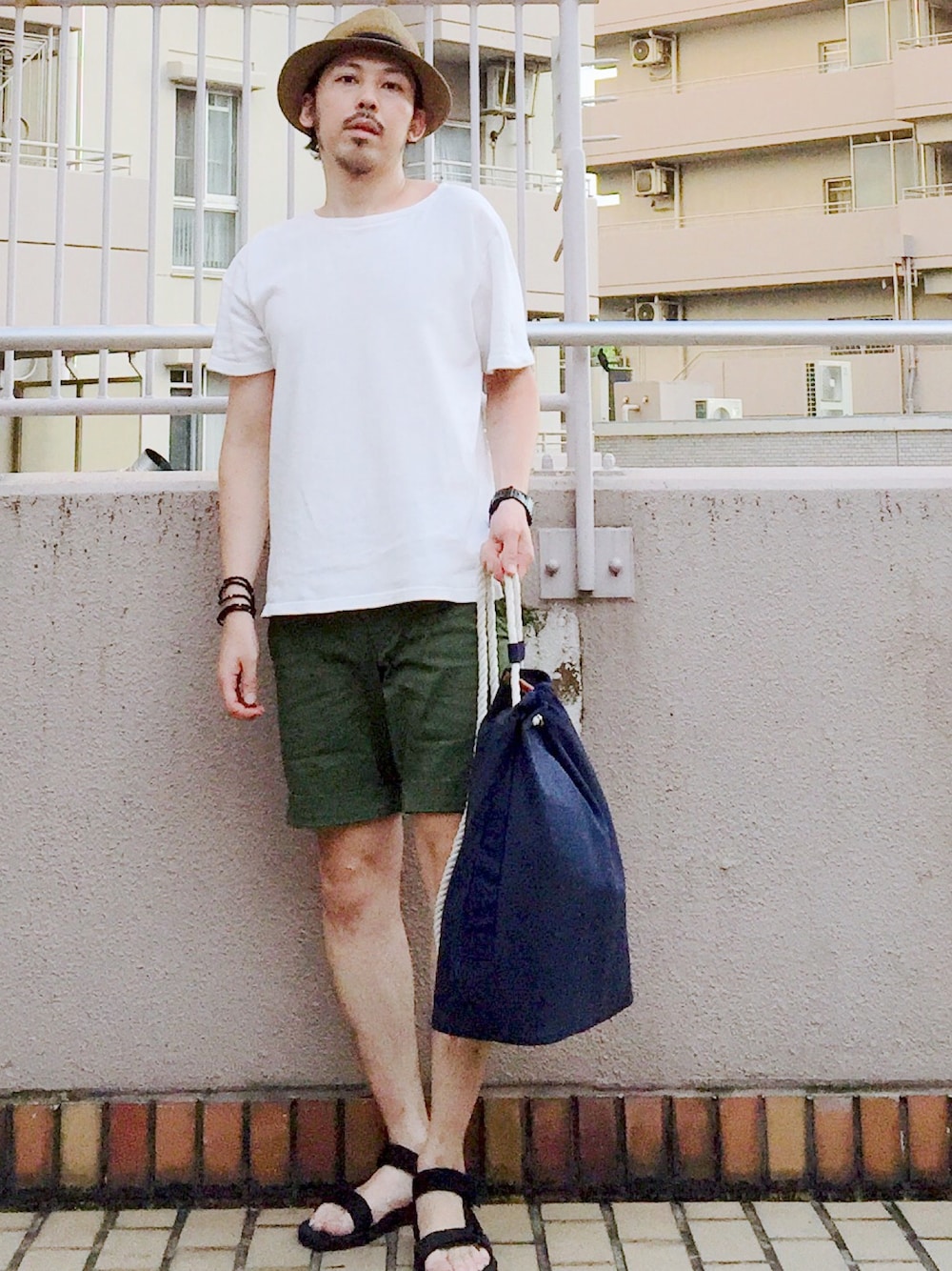 ホワイト系のTシャツ/カットソー、ブルー系のバックパック/リュック、ブラック系のサンダルを着用したメンズの夏コーディネートの1枚目の写真