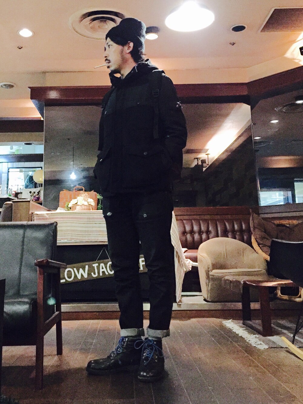 ブラック系のマウンテンパーカー、ブラック系のデニムパンツ、ブラック系のブーツを着用したメンズの秋コーディネートの1枚目の写真