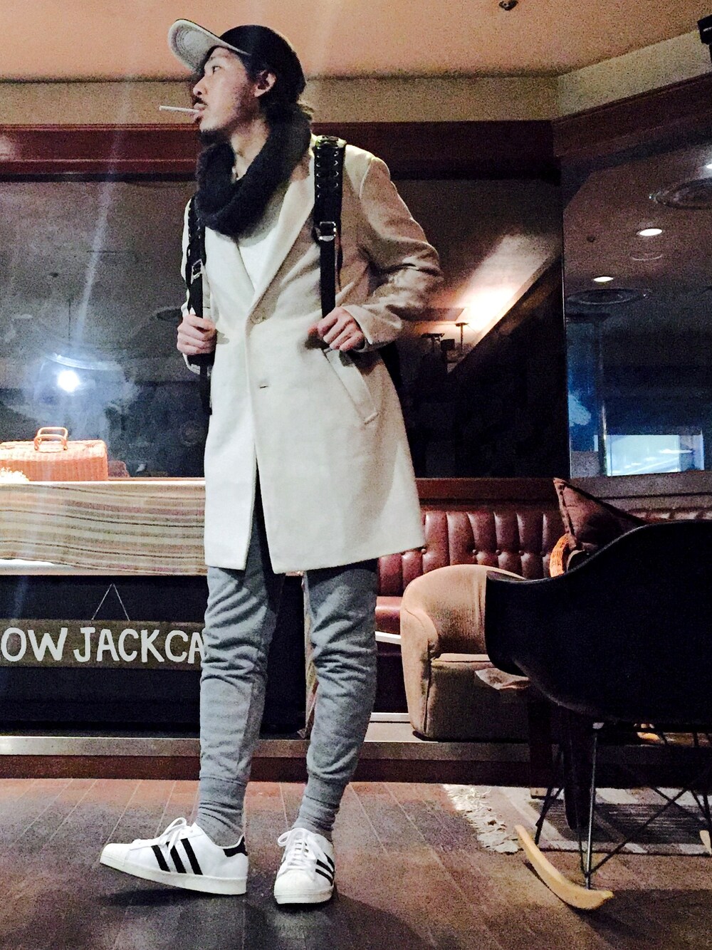 ホワイト系のチェスターコート、グレー系のその他パンツ、ブラック系のスニーカーを着用したメンズの秋コーディネートの1枚目の写真