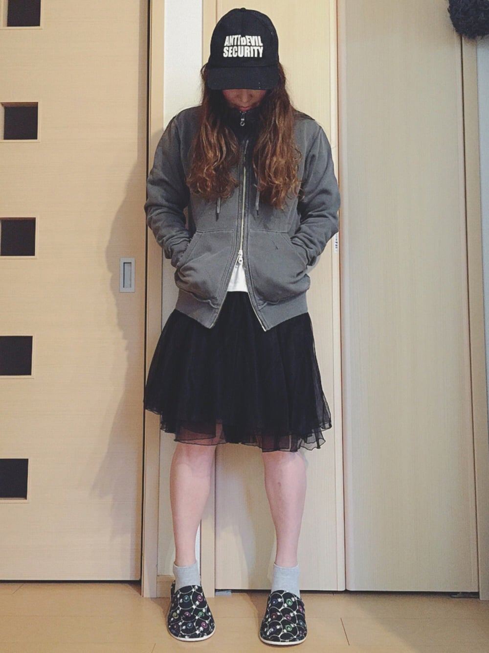 グレー系のパーカー、ブラック系のスカート、ブラック系のスニーカーを着用したレディースの春コーディネートの1枚目の写真