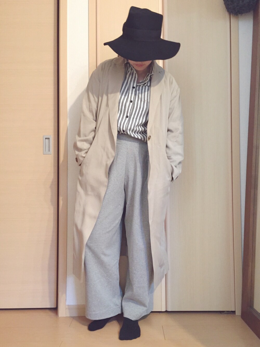 ベージュ系のチェスターコート、ブルー系のカーディガン/ボレロ、グレー系のその他パンツを着用したレディースの春コーディネートの1枚目の写真
