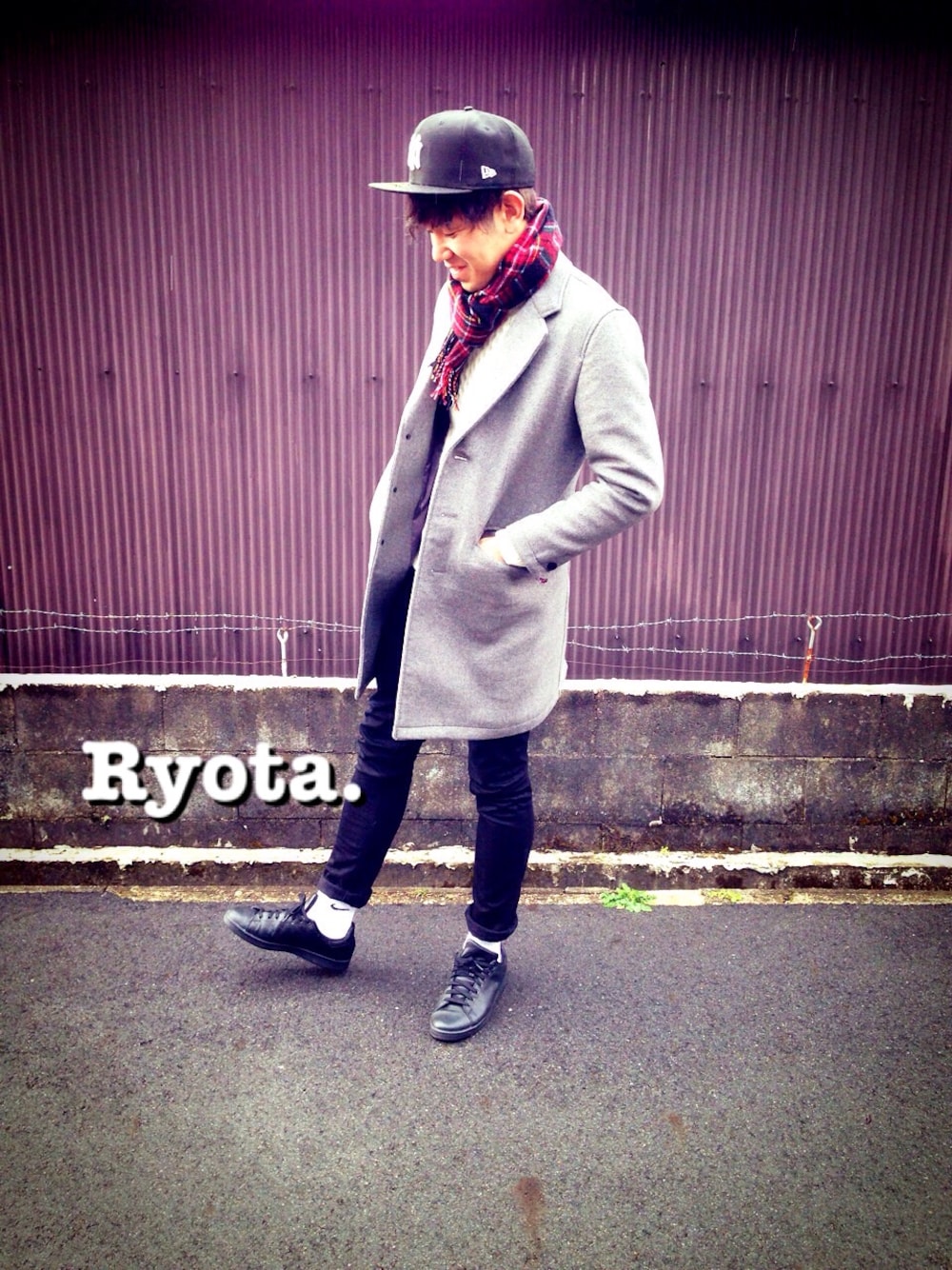 グレー系のチェスターコート、ブラック系のデニムパンツ、ブラック系のスニーカーを着用したメンズの冬コーディネートの1枚目の写真