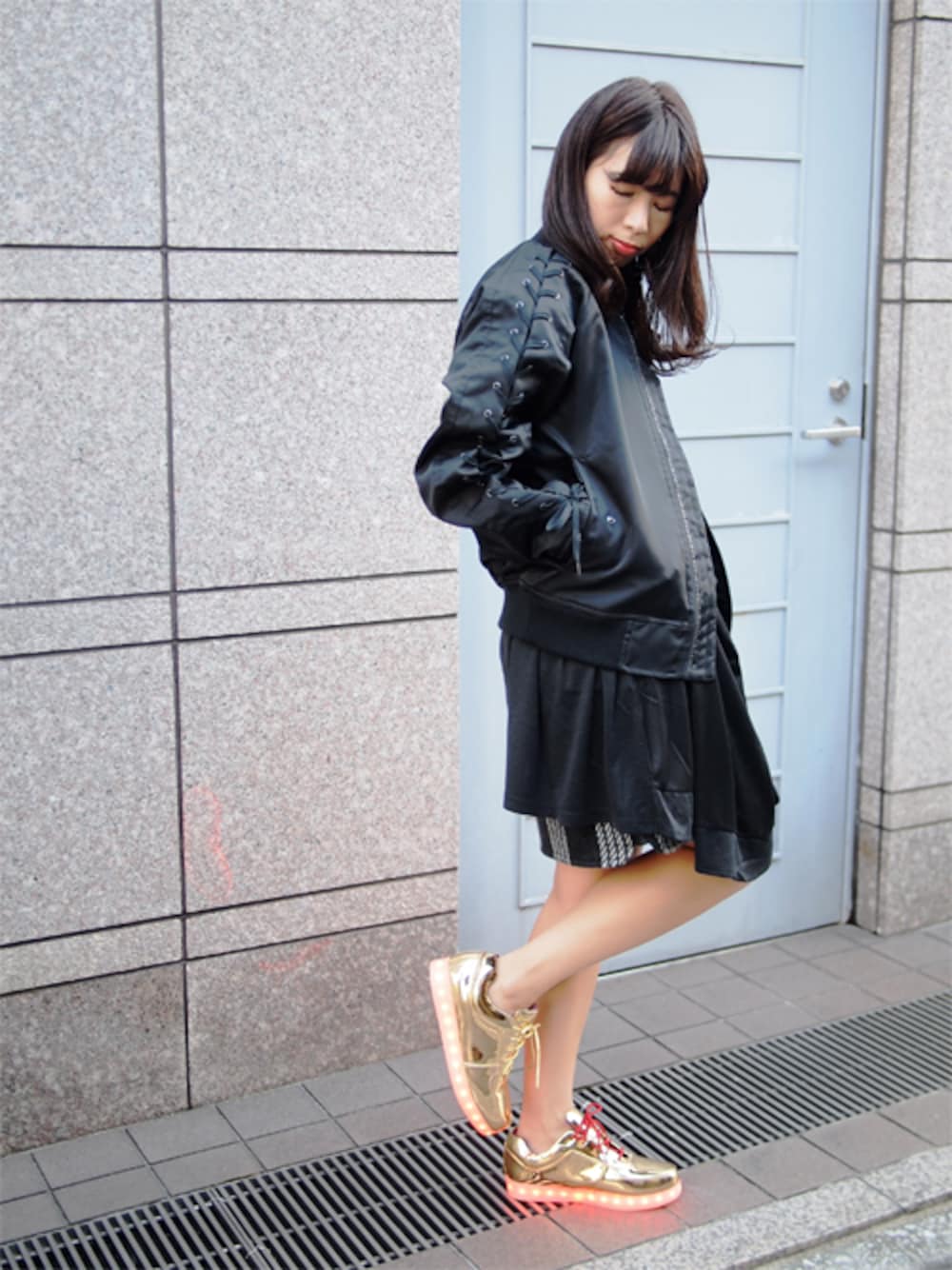 ブラック系のワンピース、ゴールド系のスニーカー、ブラック系のその他アウターを着用したレディースの秋コーディネートの1枚目の写真