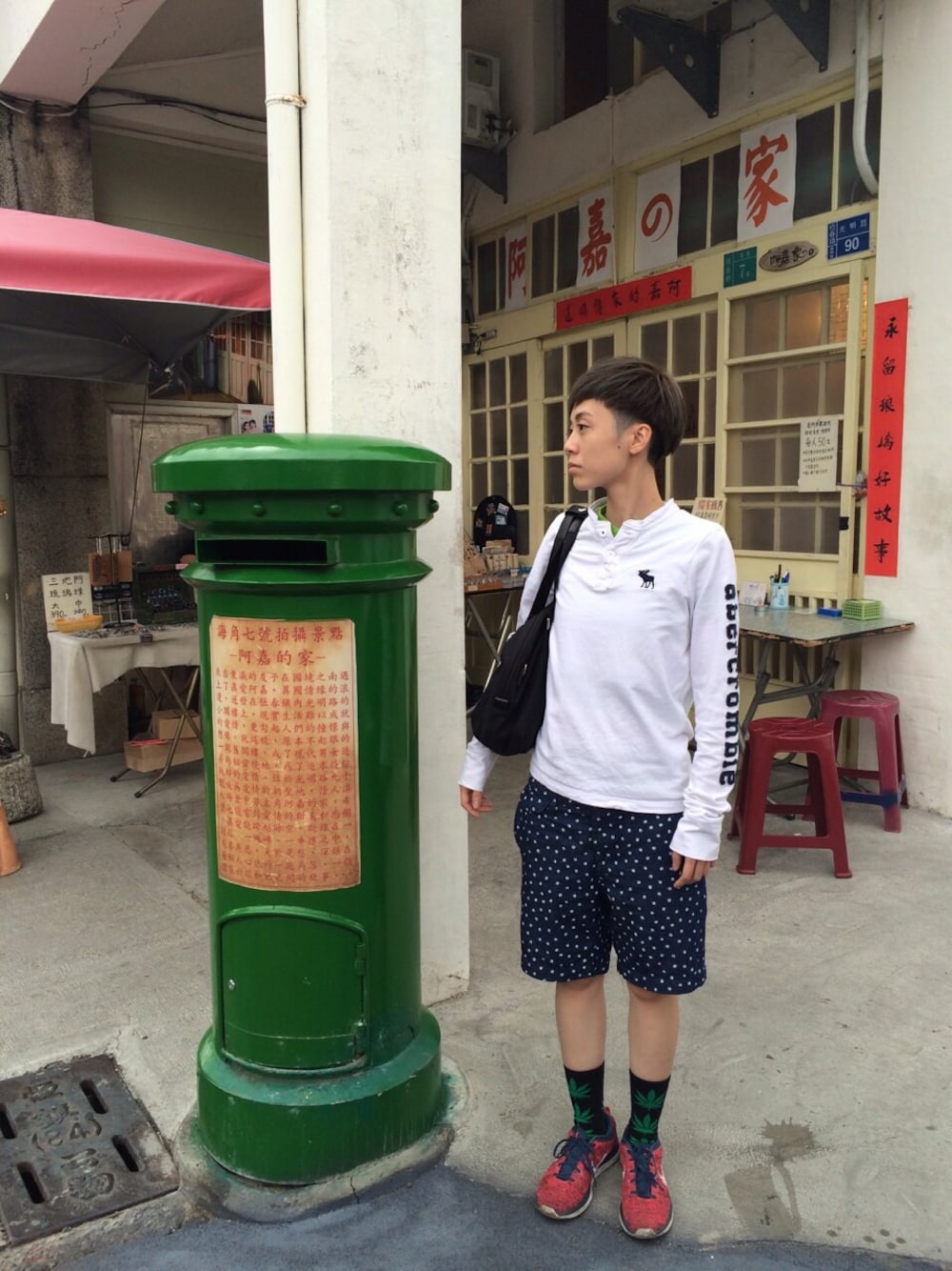 ホワイト系のその他トップス、レッド系のスニーカー、ブラック系のショルダーバッグを着用したメンズの夏コーディネートの1枚目の写真