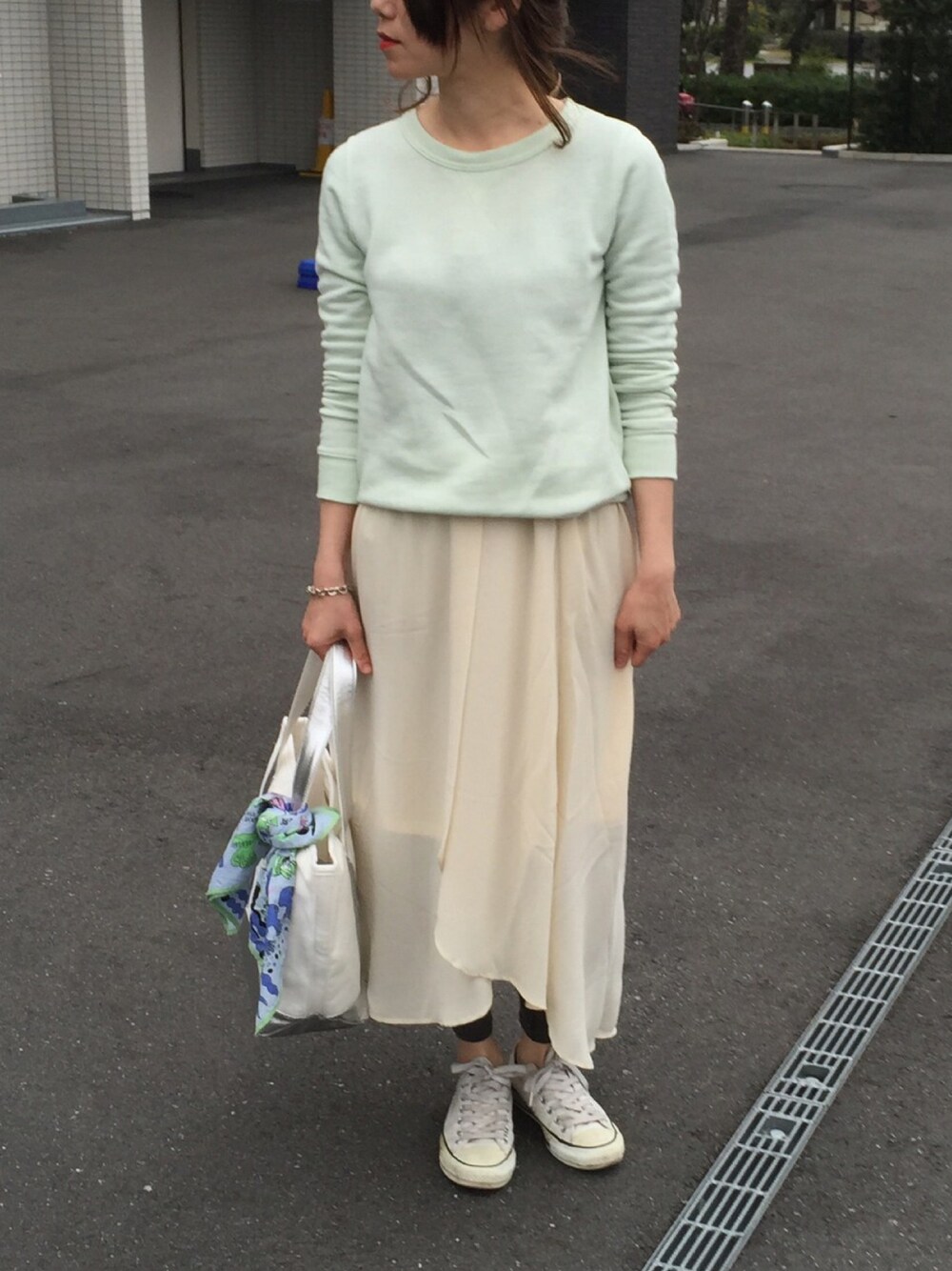 ホワイト系のスカート、ホワイト系のスニーカー、グリーン系のスウェットを着用したレディースの春コーディネートの1枚目の写真