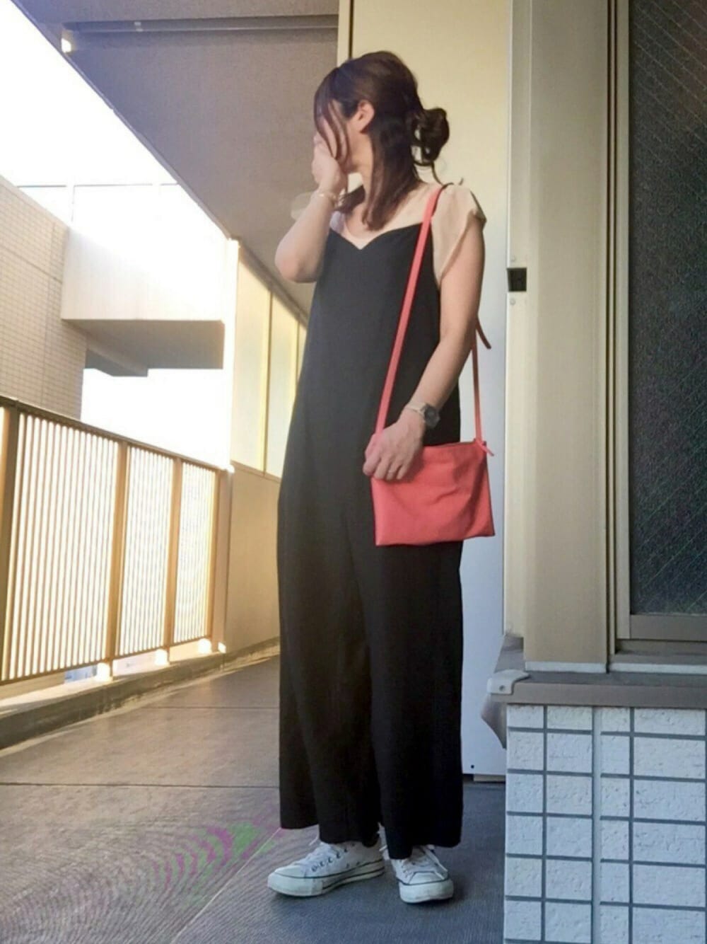 オレンジ系のショルダーバッグ、ブラック系のワンピース、ピンク系のTシャツ/カットソーを着用したレディースの夏コーディネートの1枚目の写真