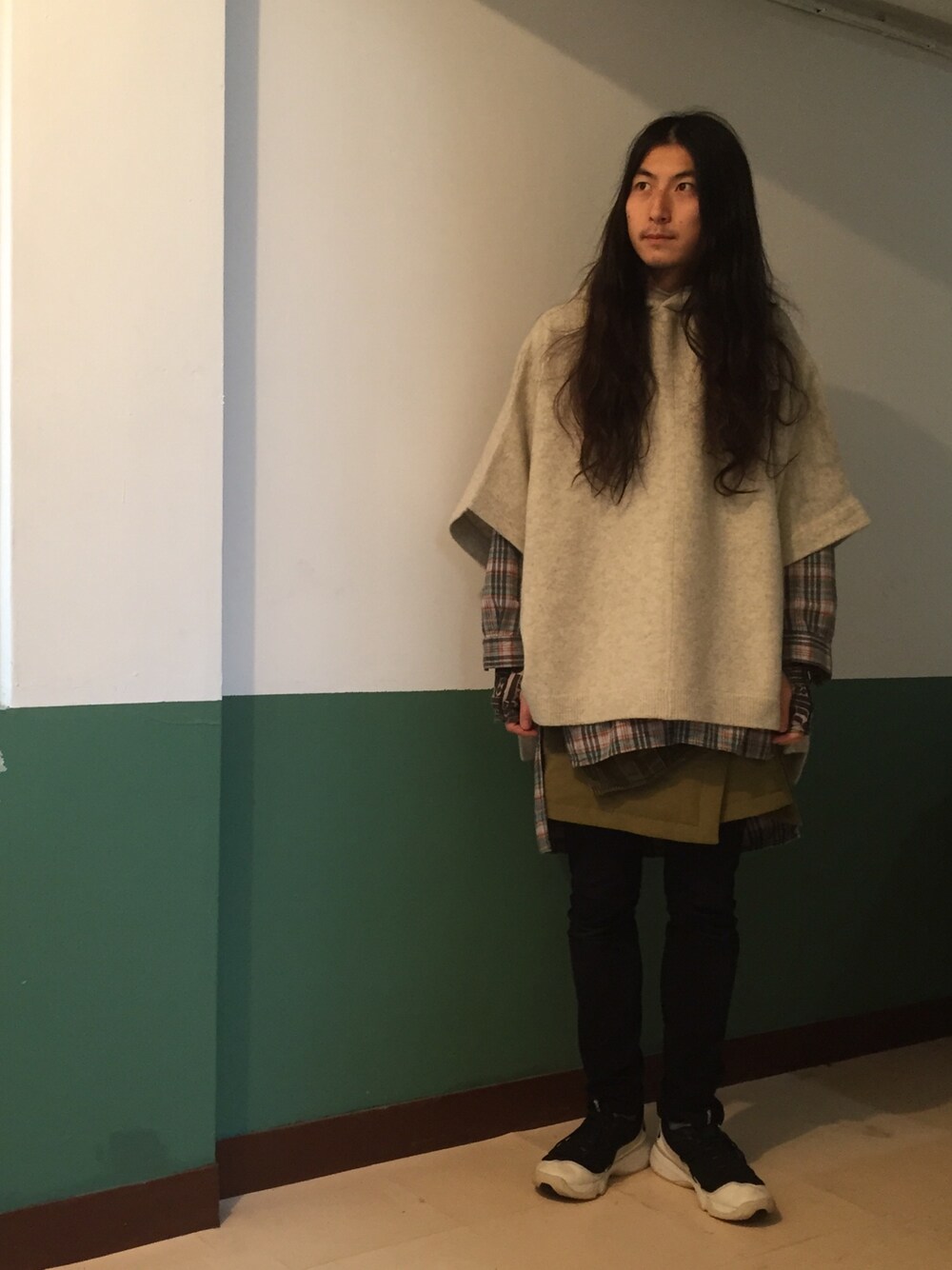 ベージュ系のニット/セーター、グリーン系のシャツ/ブラウス、グリーン系のスカートを着用したメンズの秋コーディネートの1枚目の写真