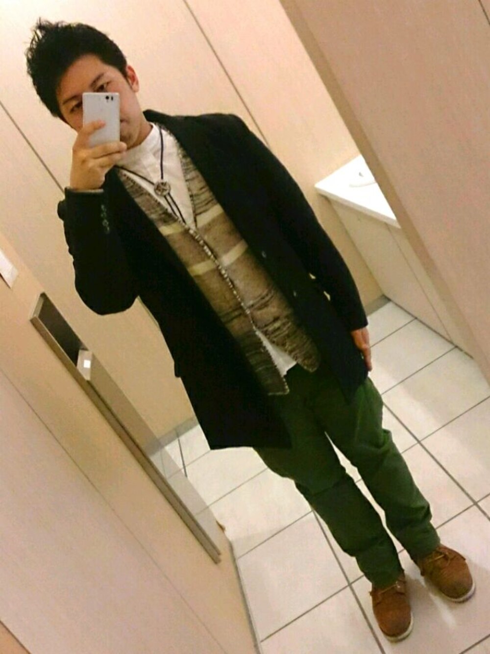 グリーン系のカーゴパンツ、ブラウン系のブーツ、ブラック系のチェスターコートを着用したメンズの冬コーディネートの1枚目の写真