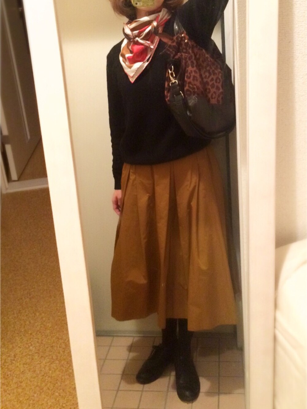 ブラック系のニット/セーター、ゴールド系のスカート、ブラウン系のショルダーバッグを着用したレディースの秋コーディネートの1枚目の写真