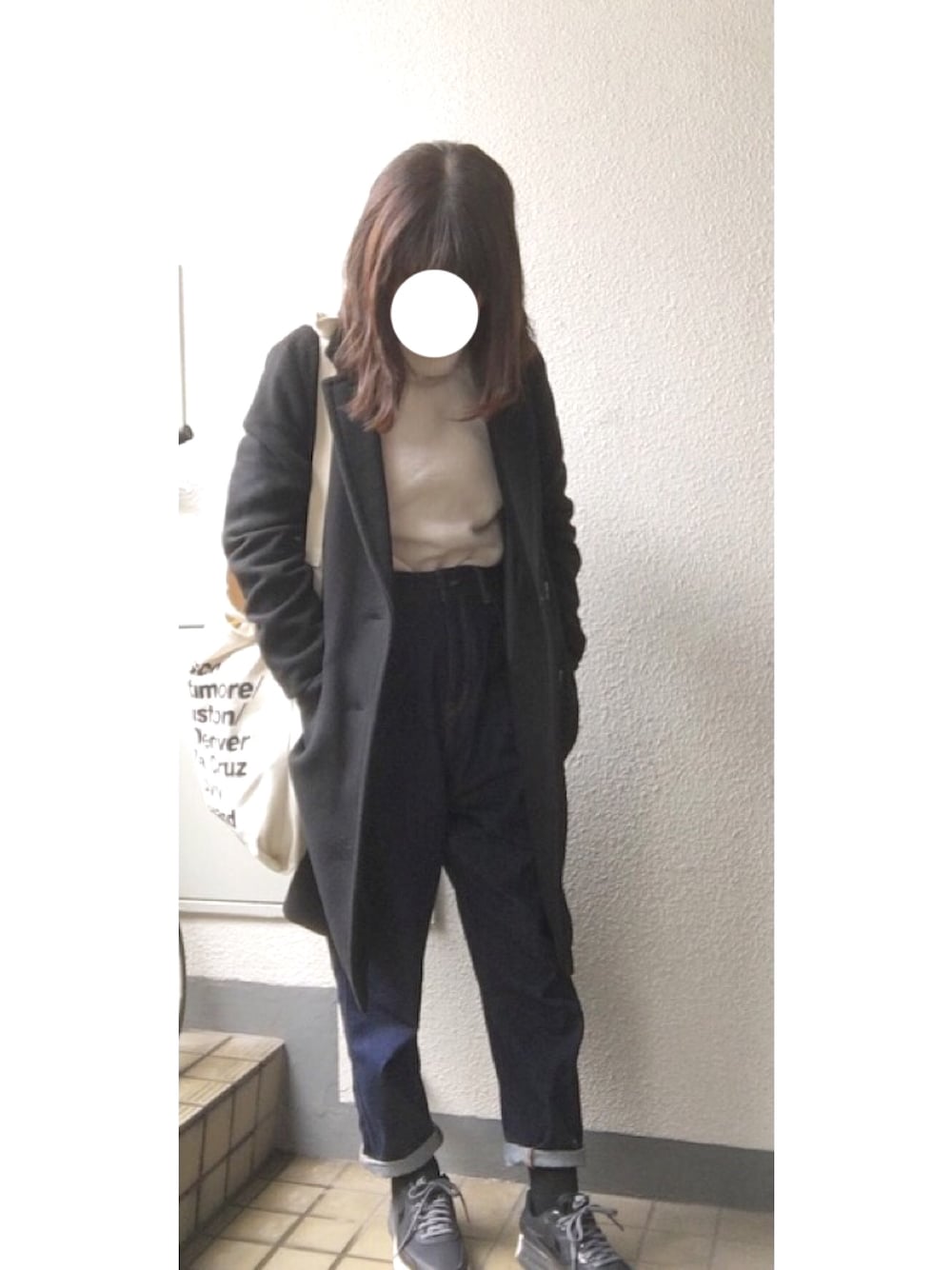 ブラック系のチェスターコート、ホワイト系のニット/セーター、ブルー系のデニムパンツを着用したレディースの秋コーディネートの1枚目の写真