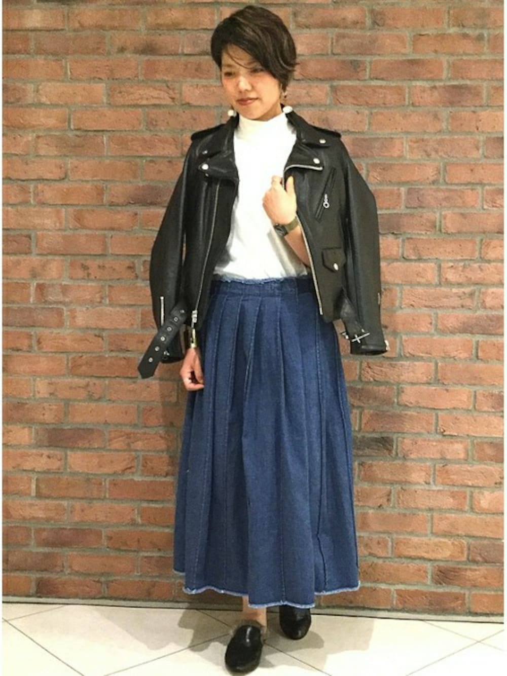 ブラック系のライダースジャケット、ブルー系のデニムスカート、ホワイト系のTシャツ/カットソーを着用したレディースの夏コーディネートの1枚目の写真