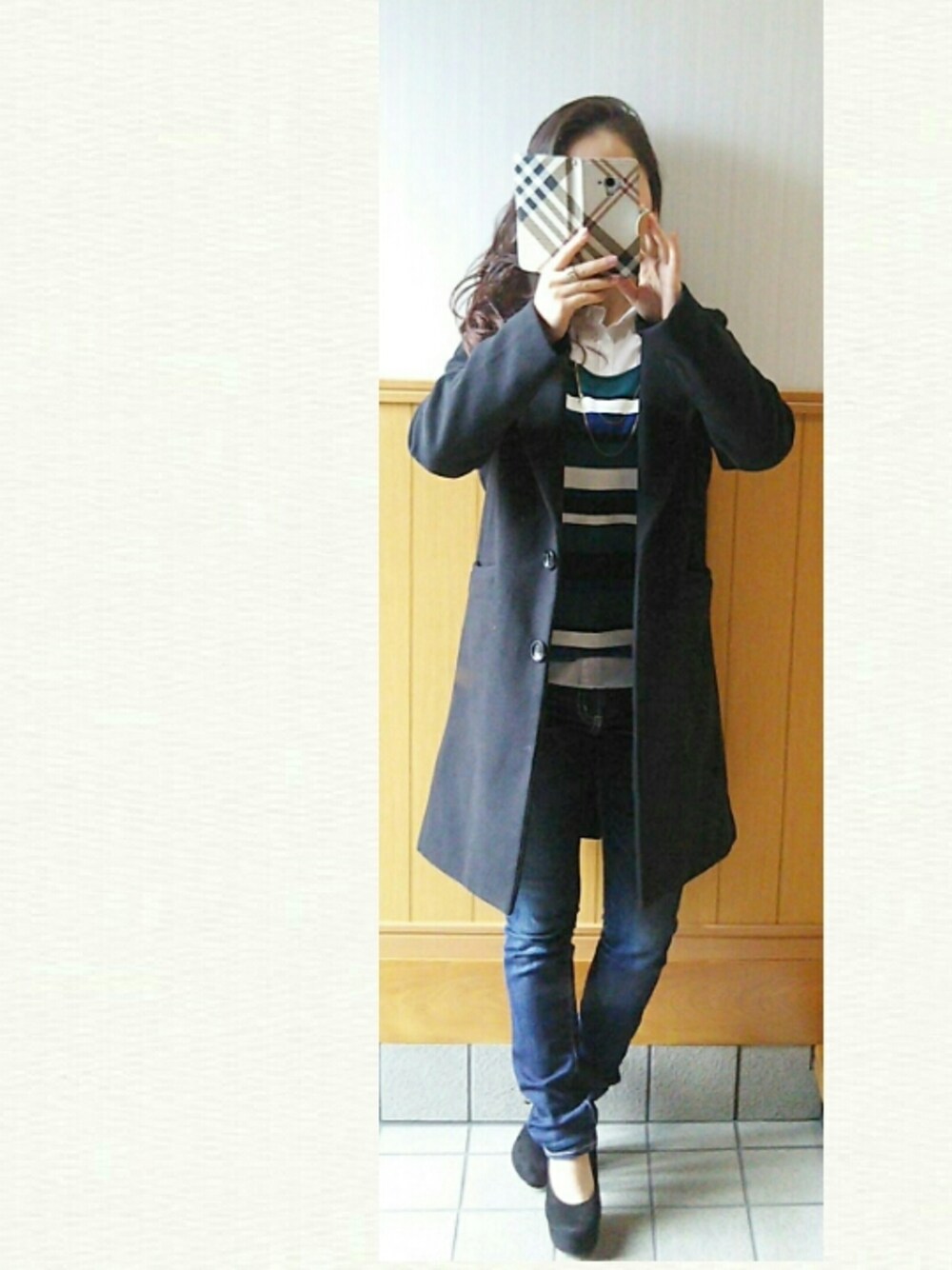 ブラック系のチェスターコート、グリーン系のニット/セーター、ブルー系のデニムパンツを着用したレディースの冬コーディネートの1枚目の写真