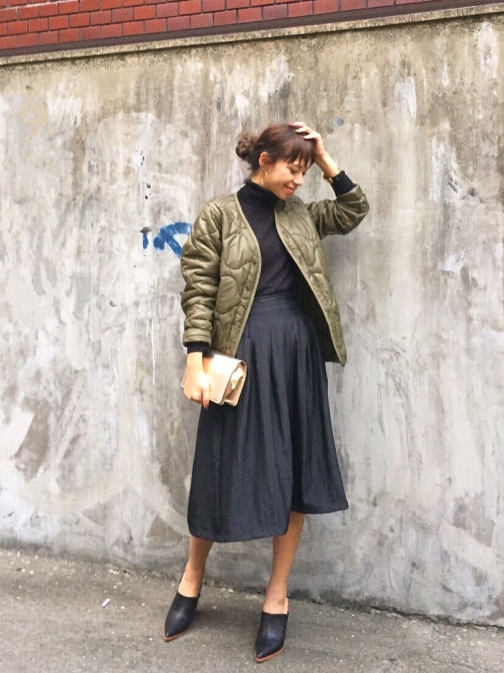 グリーン系のミリタリージャケット、ブラック系のニット/セーター、ブラック系のスカートを着用したレディースの秋コーディネートの1枚目の写真