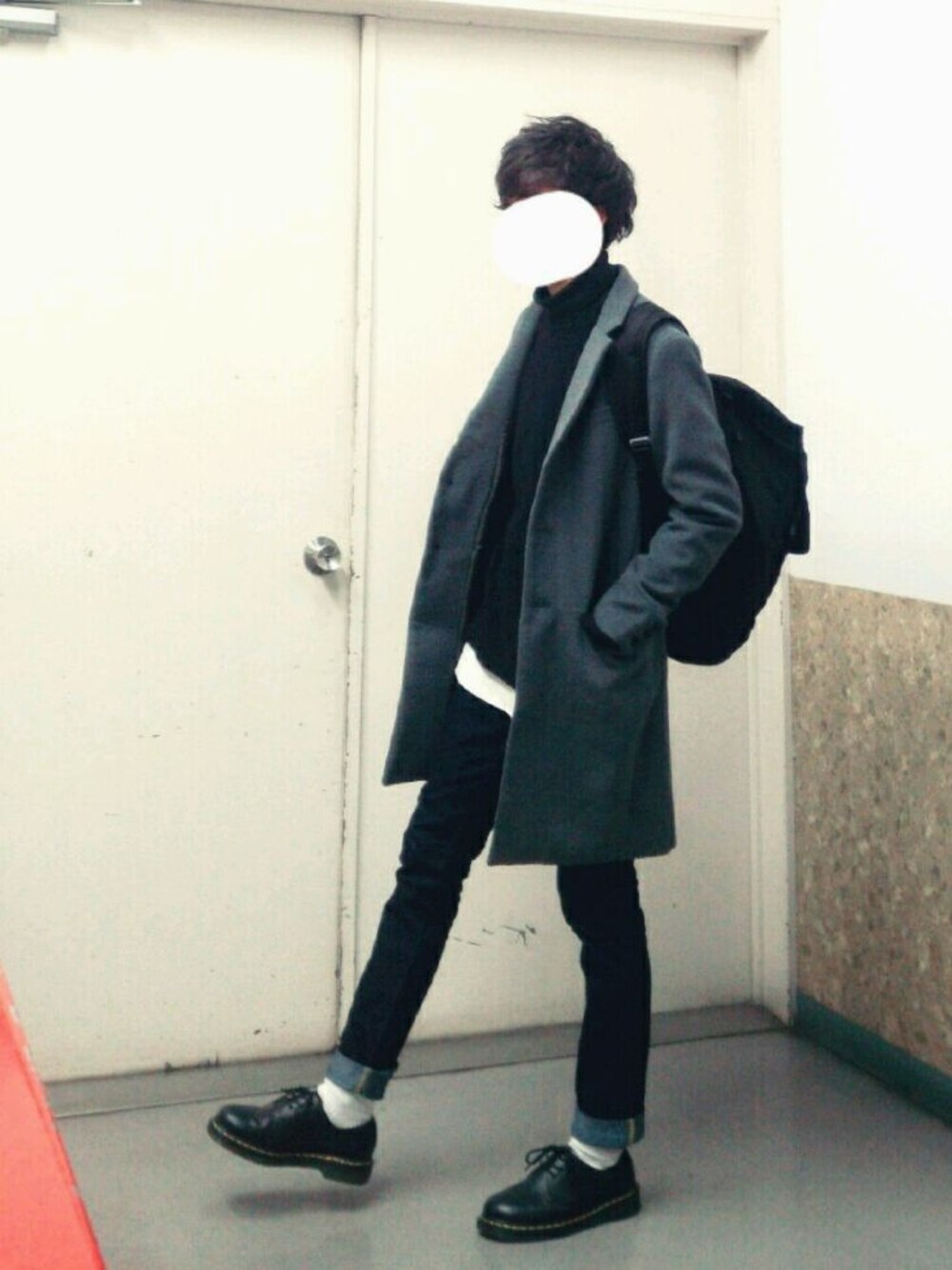 グレー系のチェスターコート、ブラック系のニット/セーター、ホワイト系のTシャツ/カットソーを着用したメンズの冬コーディネートの1枚目の写真