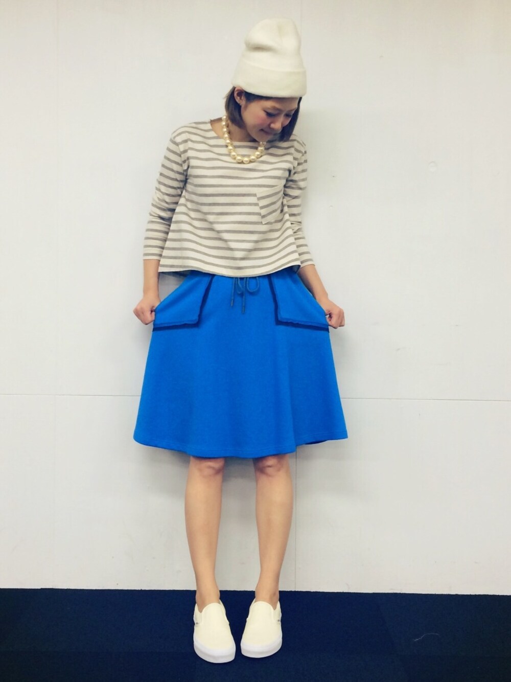 ホワイト系のスリッポン、グレー系のTシャツ/カットソー、ブルー系のスカートを着用したレディースの冬コーディネートの1枚目の写真