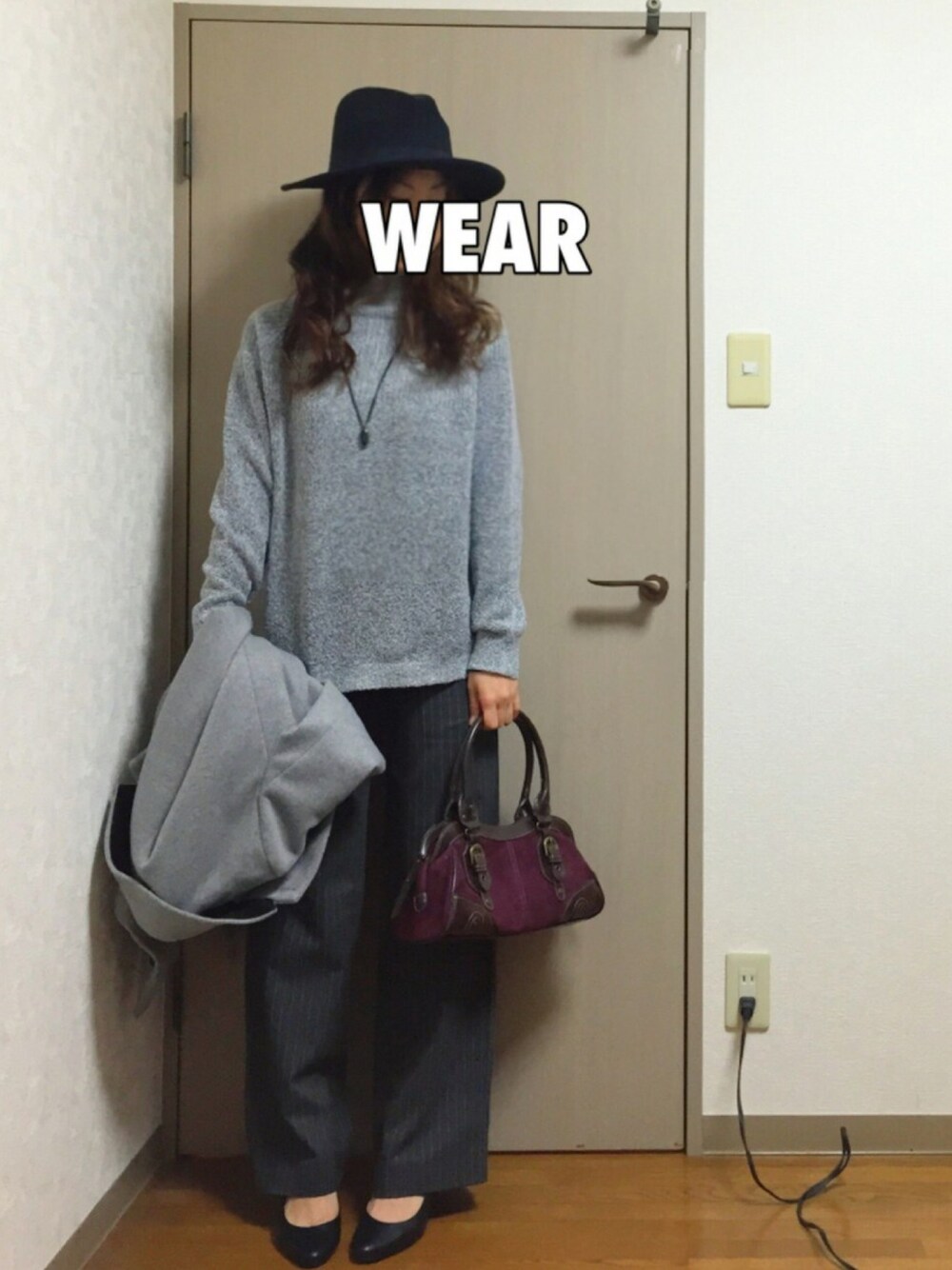 グレー系のニット/セーター、グレー系のチェスターコート、レッド系のハンドバッグを着用したレディースの秋コーディネートの1枚目の写真