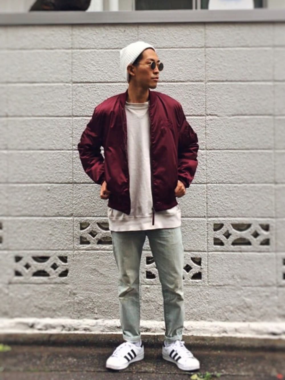 レッド系のMA-1、ベージュ系のスウェット、ブルー系のデニムパンツを着用したメンズの秋コーディネートの1枚目の写真