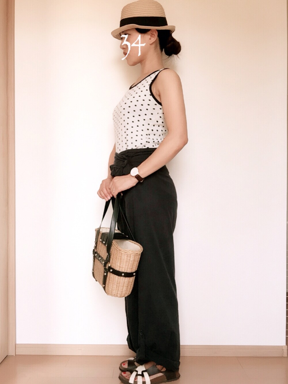 ブルー系のパンツ、ホワイト系のサンダル、ベージュ系のかごバッグを着用したレディースの夏コーディネートの1枚目の写真
