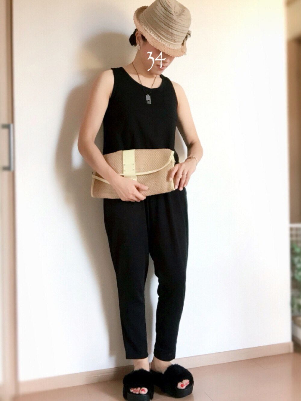 ブラック系のサロペット/オーバーオール、ベージュ系のクラッチバッグ、ブラック系のサンダルを着用したレディースの夏コーディネートの1枚目の写真