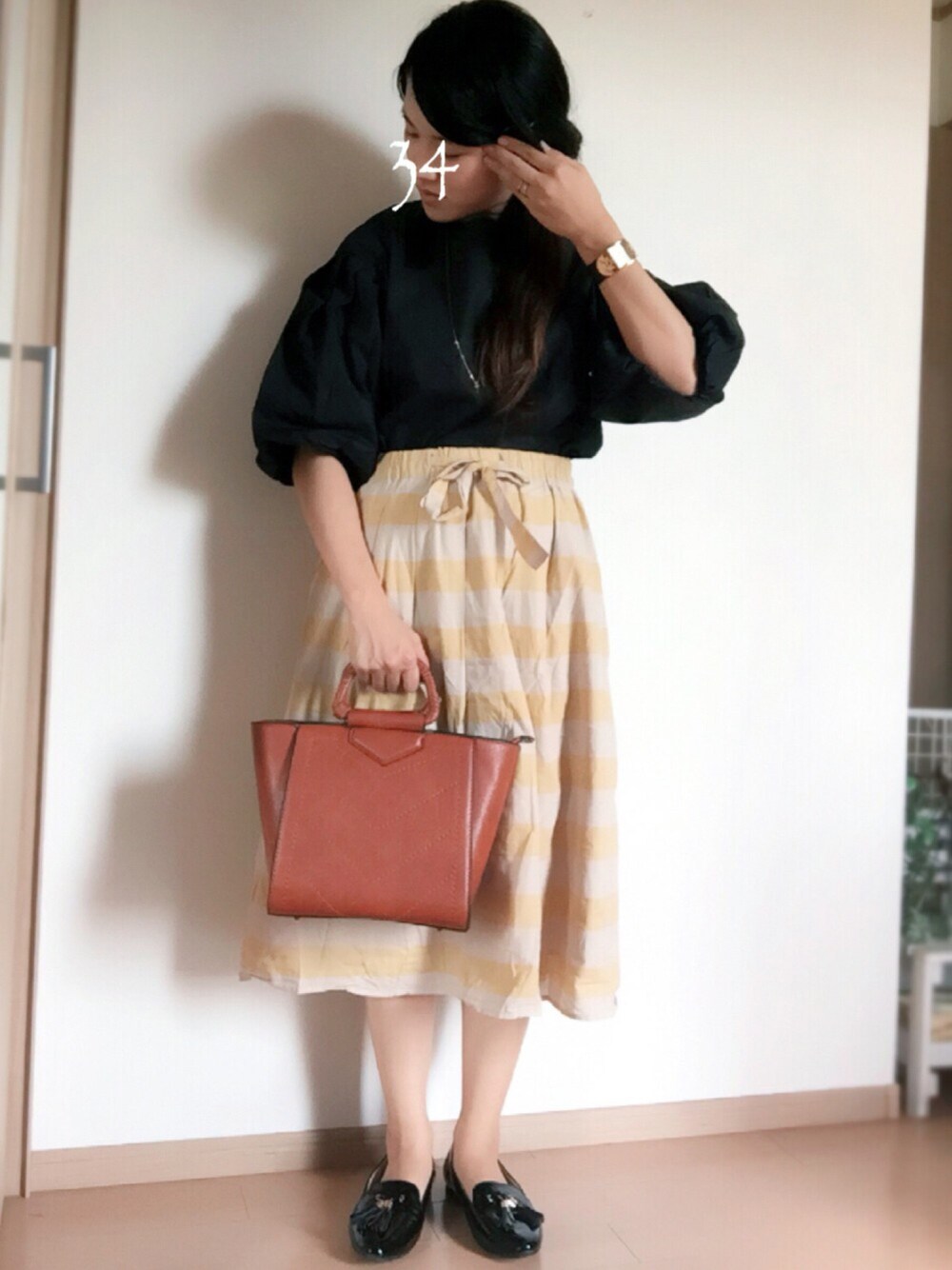 ブラック系のシャツ/ブラウス、ブラウン系のバッグ、イエロー系のスカートを着用したレディースの秋コーディネートの1枚目の写真