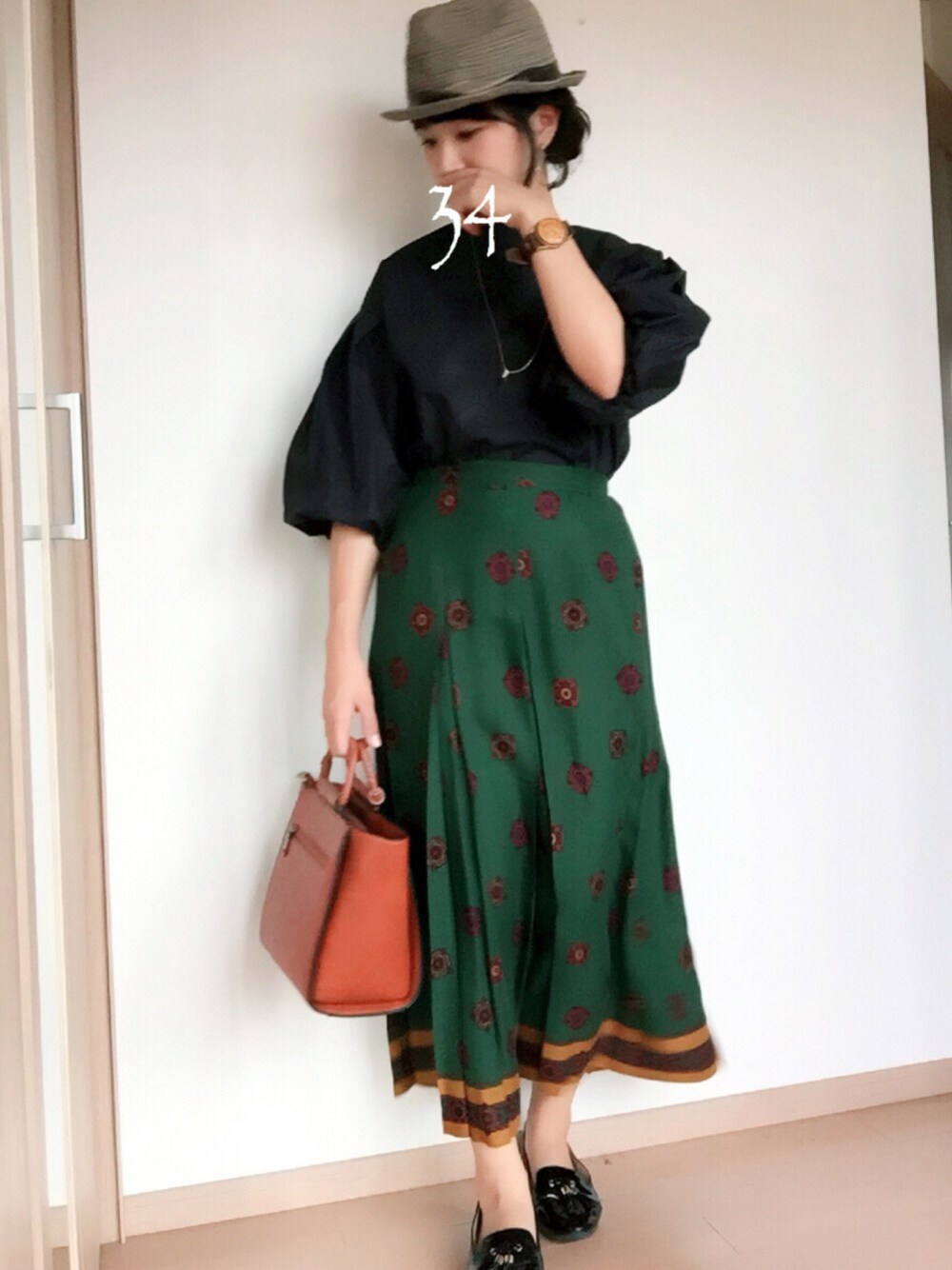 ブラック系のシャツ/ブラウス、グリーン系のスカート、ブラウン系のバッグを着用したレディースの秋コーディネートの1枚目の写真