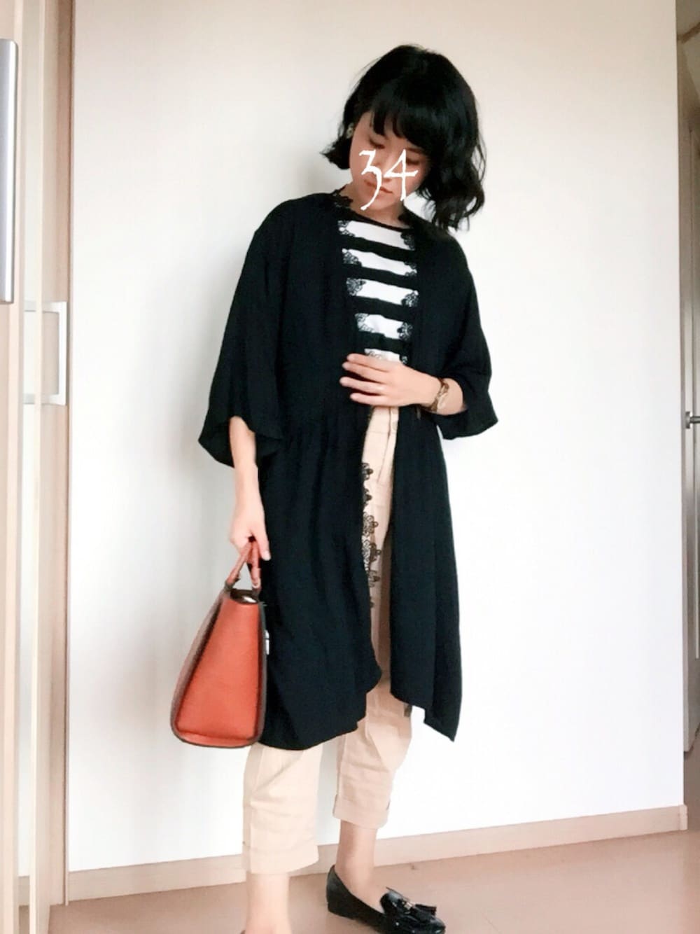 ブラック系のカーディガン/ボレロ、ブラウン系のバッグ、ベージュ系のチノパンツを着用したレディースの秋コーディネートの1枚目の写真