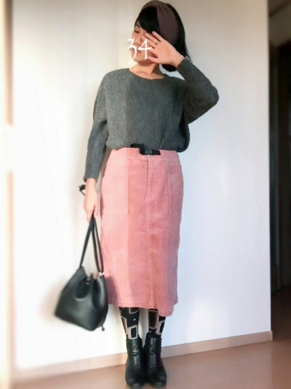ピンク系のスカート、ブラック系のショルダーバッグ、ブラック系のブーティを着用したレディースの秋コーディネートの1枚目の写真
