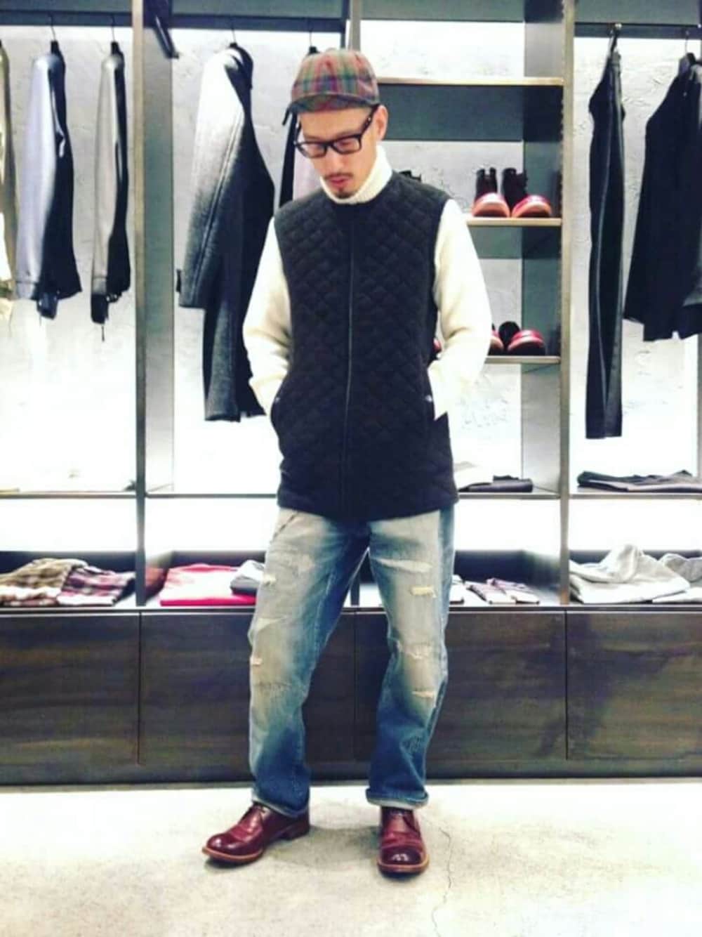 ホワイト系のニット/セーター、ブラック系のダウンベスト、ブルー系のデニムパンツを着用したメンズの秋コーディネートの1枚目の写真